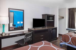 a hotel room with a desk with a television and a bed at Super 8 by Wyndham Pensacola in Pensacola