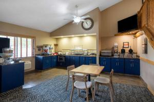 a kitchen with blue cabinets and a table and a clock at AmericInn by Wyndham Two Harbors Near Lake Superior in Two Harbors