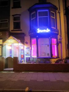 un bâtiment avec des lumières roses et bleues sur lui dans l'établissement Sorrento House, à Blackpool