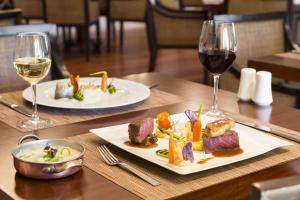 deux assiettes de nourriture sur une table avec des verres à vin dans l'établissement Dolce CampoReal Lisboa, à Turcifal