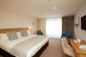a hotel room with a large bed and a desk and chair at Old Hunstanton Le Strange Arms Hotel in Hunstanton