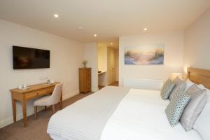 a bedroom with a bed and a desk and a television at Old Hunstanton Le Strange Arms Hotel in Hunstanton