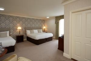 a hotel room with two beds and a door at Old Hunstanton Le Strange Arms Hotel in Hunstanton