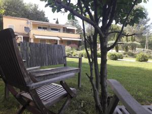 a wooden bench sitting in the grass next to a tree at Les Cerises in Saint-Saturnin-lès-Apt