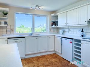 a kitchen with white cabinets and a large window at Island View in St. Davids
