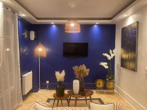 a living room with a blue wall with a tv at L'AMAZONIE - Lovely apartment near to the train station and Orly Airport in Juvisy-sur-Orge