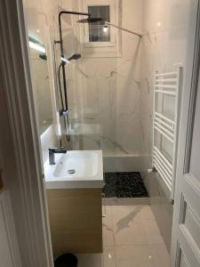 a white bathroom with a sink and a shower at L'AMAZONIE - Lovely apartment near to the train station and Orly Airport in Juvisy-sur-Orge