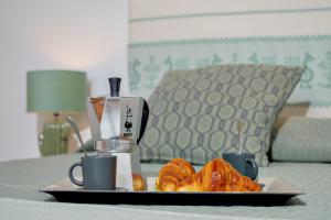 a plate of croissants and coffee cups on a table at Appartamento Botanico - SHERDENIA Luxury Apartments in Santa Marinella