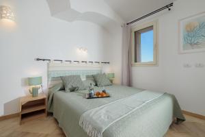 una camera da letto con un letto e un vassoio di frutta; di Appartamento Botanico - SHERDENIA Luxury Apartments a Marinella