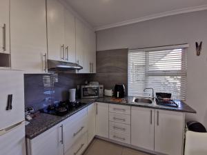 a kitchen with white cabinets and a sink at Zebra Place in Cape Town