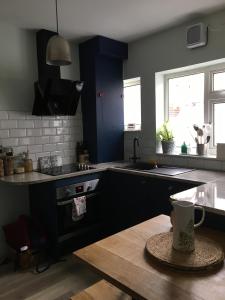 een keuken met blauwe kasten, een tafel en een wastafel bij Belmont Gem in Knaresborough
