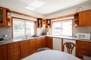 a kitchen with wooden cabinets and a sink and a window at Private Gardened House - 5min from the beach in Viana do Castelo