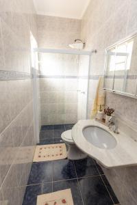 La salle de bains blanche est pourvue d'un lavabo et d'une douche. dans l'établissement Hospedaria do Lago, à Espirito Santo Do Pinhal