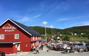 a group of people standing outside of a red barn at Pålberget in Råkvåg