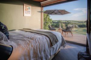 Johnston的住宿－Tawny Lodge - Luxurious 1 Bedroom - Blossom Farm，一间卧室配有一张床,阳台配有遮阳伞