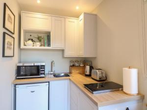 a small kitchen with white cabinets and a microwave at The Lodge at Middleton House in Church Leigh