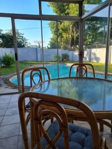 een glazen tafel met 2 stoelen en een zwembad bij African Cycad Holiday Home in Durban