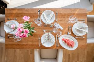 een houten tafel met borden en bloemen erop bij Skyflats Vienna - Rooftop Apartments in Wenen