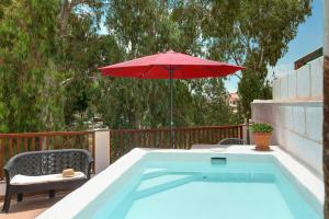 a red umbrella sitting next to a swimming pool at Holiday Cottage Santa Lucía in Santa Lucía