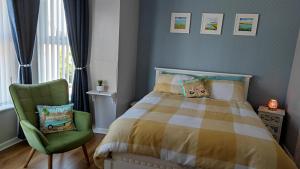 a bedroom with a bed and a green chair at Luxury 3 bedroom house with peaceful garden, sleeps 6 and 2 mins to beach in Bundoran