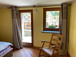 a bedroom with a bed and a chair and a window at Maison Bosc, Champorcher in Champorcher