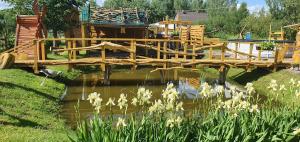 a wooden bridge over a pond in a garden at Viesu māja Kaķis krūzē in Folvarcīši