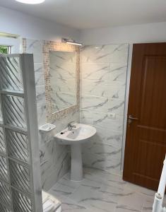 ein Bad mit einem Waschbecken und einem Spiegel in der Unterkunft Han Pizza&Pasta in Domneşti