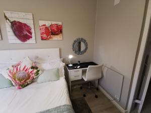 a bedroom with a bed and a desk with a mirror at Protea Suite in Bellville