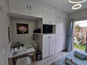 a kitchen with white cabinets and a desk in a room at Protea Suite in Bellville
