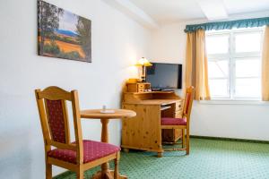 a room with a table and chairs and a television at Hotel & Restaurant Brauner Hirsch Osterwieck in Osterwieck