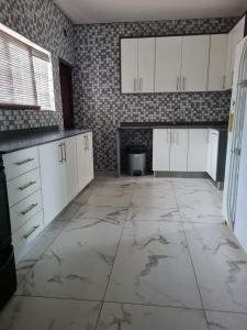 a kitchen with white cabinets and a tile wall at African Cycad Holiday Home in Durban