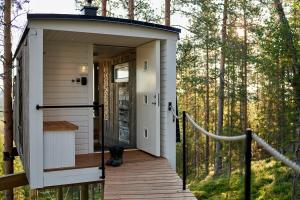 a tiny house with a deck in the woods at Swedish Treehouse 