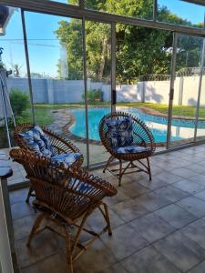 um pátio com 2 cadeiras e uma piscina em African Cycad Holiday Home em Durban
