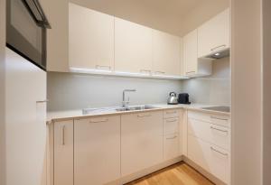 uma cozinha com armários brancos e um lavatório em Argentieri Apartment em Bolzano