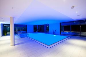 a large swimming pool in a room with blue lighting at Landhotel Annelie in Preußisch Oldendorf