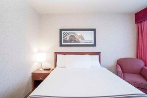a hotel room with a bed and a chair at Sandman Hotel Penticton in Penticton