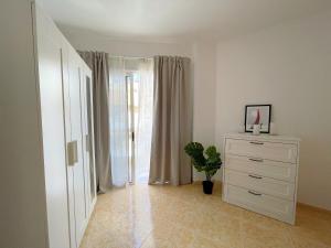 a white bedroom with a dresser and a window at Edificio Don Diego in Los Cristianos