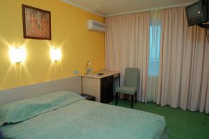 カームヤネツィ・ポジーリシクィイにある7 Days Hotel Kamyanets-Podilskyiのベッドとデスクが備わるホテルルームです。
