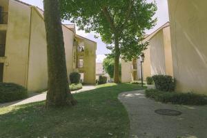 a walkway between two buildings with trees in a yard at Luka's charming apartment near Disneyland in Magny-le-Hongre