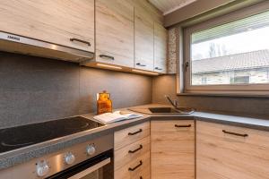 a kitchen with wooden cabinets and a sink and a window at Family Bungalow De Strandjutter 8 people in Middelkerke