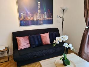 um sofá preto numa sala de estar com um vaso de flores em Appartement avec rez de jardin à Disneyland em Montévrain
