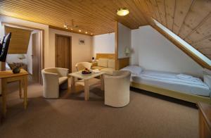 スピンドレルフ・ムリンにあるHotel Tři Růžeのベッド、テーブル、椅子が備わるホテルルームです。