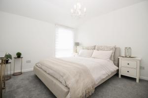 a white bedroom with a large bed and a window at Katie's house in Cumbernauld
