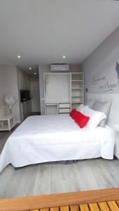 1 dormitorio con cama blanca grande y almohada roja en Marina Atico Penthouse, en Puerto de la Cruz