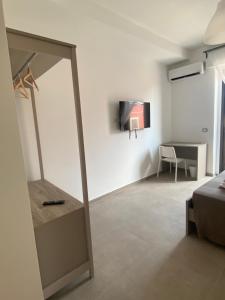 a room with a mirror and a tv on a wall at AEROPORTO KATANÈ ROOMS in Catania