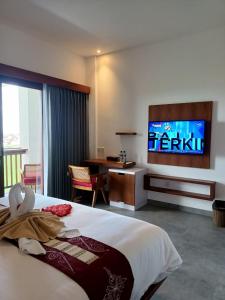 a bedroom with a bed with a tv on the wall at The Kd Suites & Coffee Shop in Munggu