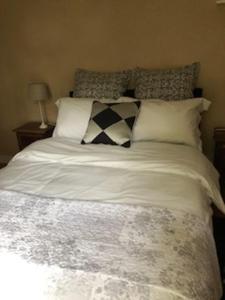 um quarto com uma cama com lençóis brancos e almofadas em Cottage Desmaisons em Saint-Just-le-Martel