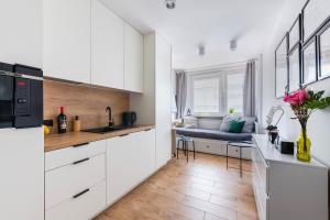 a kitchen with white cabinets and a table with flowers at Śliska 3 - studio - 100m od Złotych Tarasów oraz 200m od Dworca Centralnego, piękny widok na panoramę Warszawy - Wifi - Smart TV 55 cali - Better Rental in Warsaw