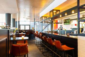 restauracja z barem z brązowymi krzesłami w obiekcie Bastion Hotel Almere w Almere