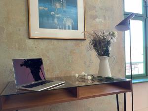 a glass table with a laptop and a vase of flowers at traumHaff- Endless Summer Loft, privates NORDICSPA, Kamin, Hund, 400m zum Wasser in Rieth
